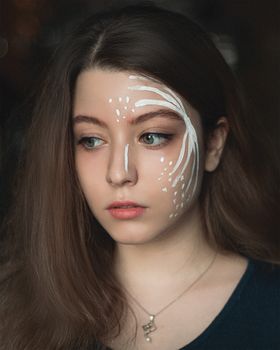 Close-up portrait of a woman with artistic face paint highlighting creativity.
