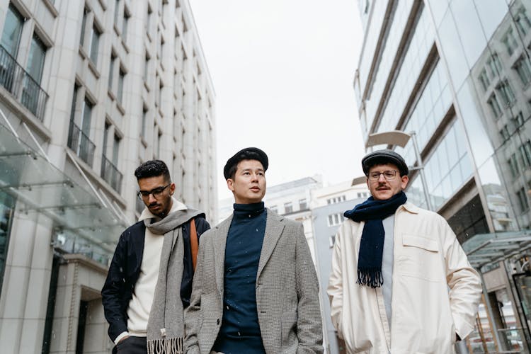 A Group Of Men In Winter Clothes Walking Between The Buildings