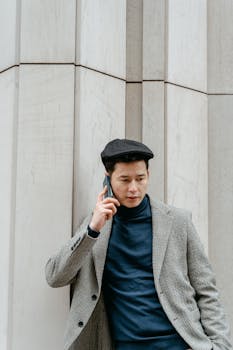 Urban professional in a stylish outfit using a smartphone outdoors.