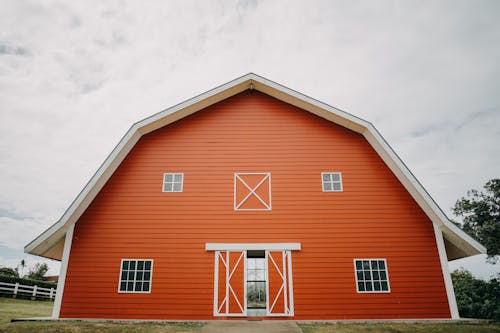 An Orange Barn House Under White Clouds