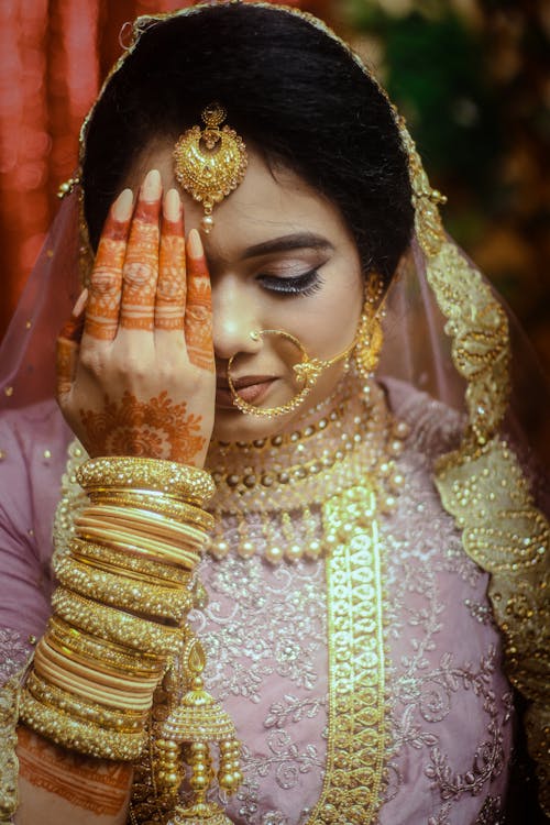 A Woman with Face Jewelries  and Mehndi Covering Half of Face with Her Hand