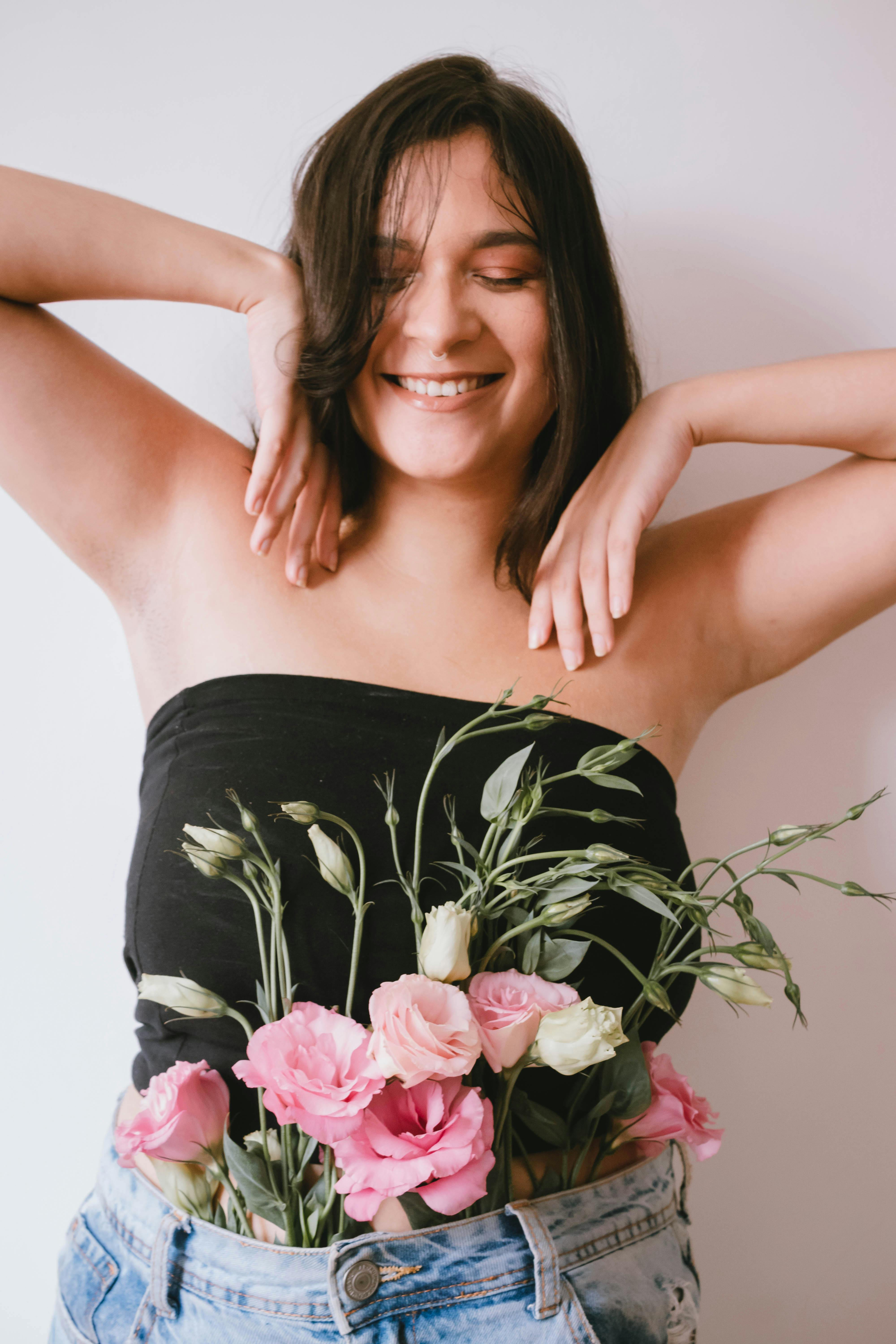Joyful woman posing with flowers, eyes closed, in a casual setting, São Paulo.