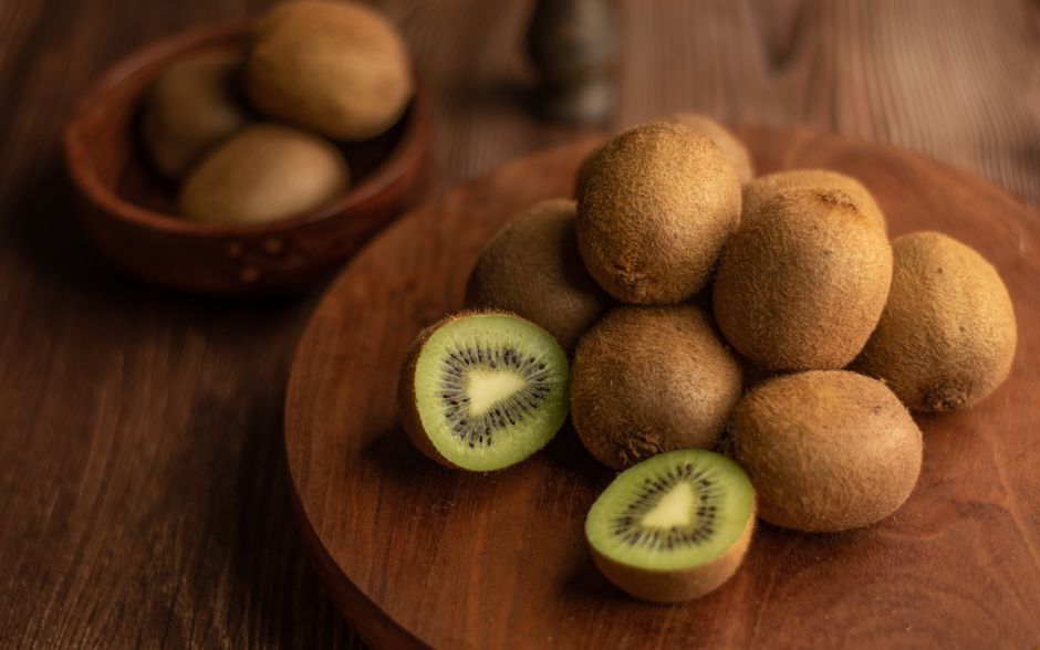 Halved and whole kiwi fruit on a wooden board, showing the green flesh used as a bulgogi tenderizer substitute