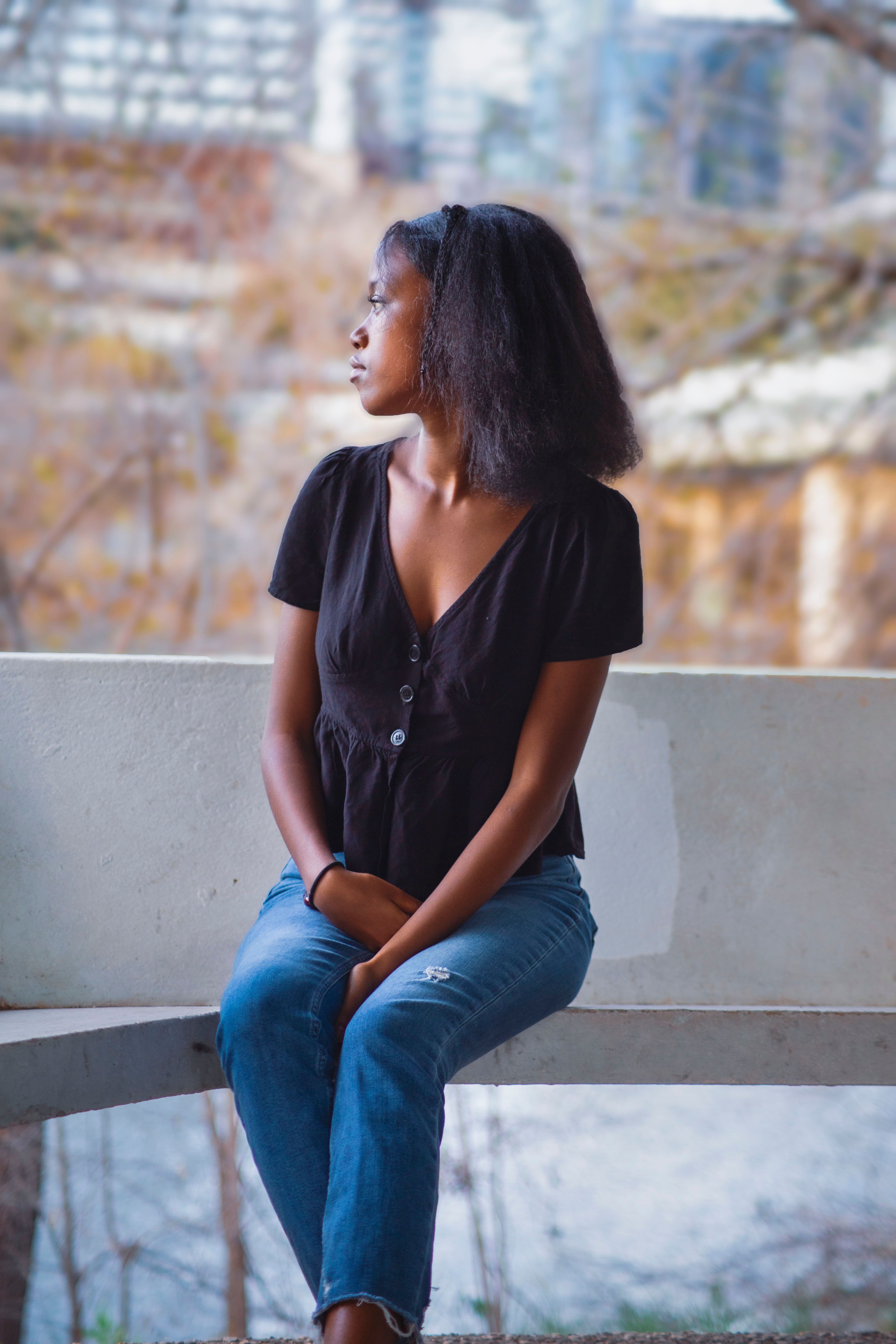 Woman in White Top and Denim Jeans Sitting on a Barrier · Free Stock Photo