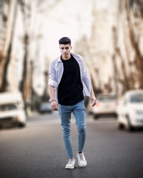 Free Stylish young man in black and denim on blurred urban street with white shoes. Stock Photo