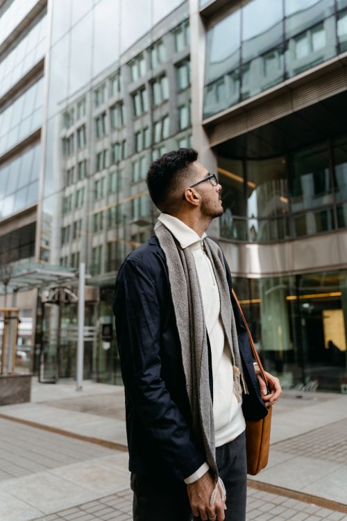 Free Young businessman in stylish attire outside modern glass office building. Stock Photo