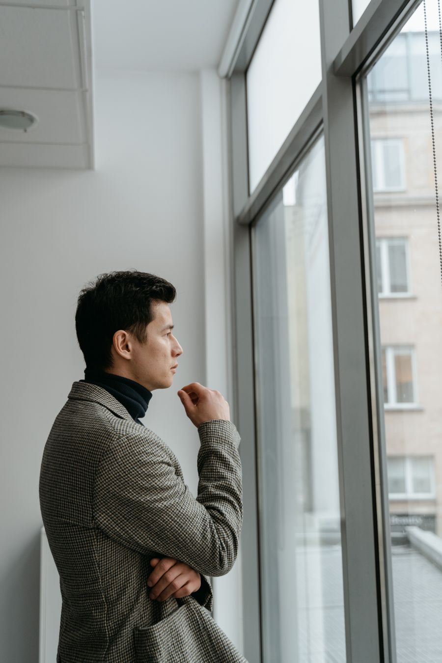 A person looking thoughtful and reflective near a window