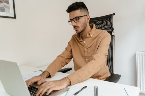 Free A Man in Brown Long Sleeves Typing on His Laptop Stock Photo