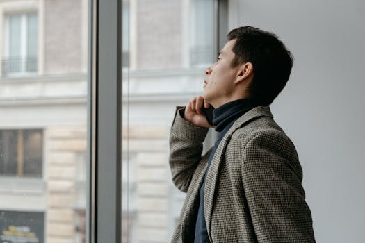 Side profile of a thoughtful businessman gazing out of a window in a contemporary office setting.