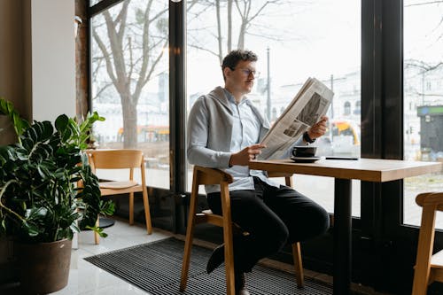 Um Homem Lendo Jornal Dentro De Uma Cafeteria