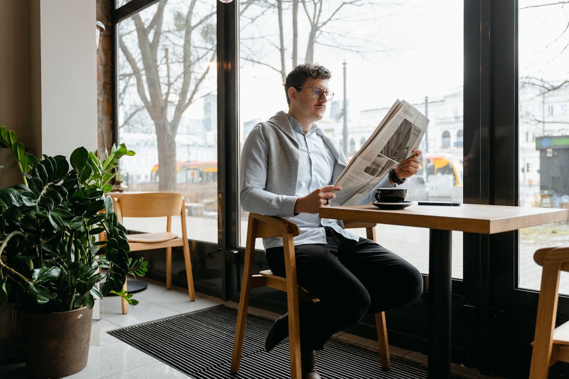 A Man Reading Newspaper inside a Coffee Shop
