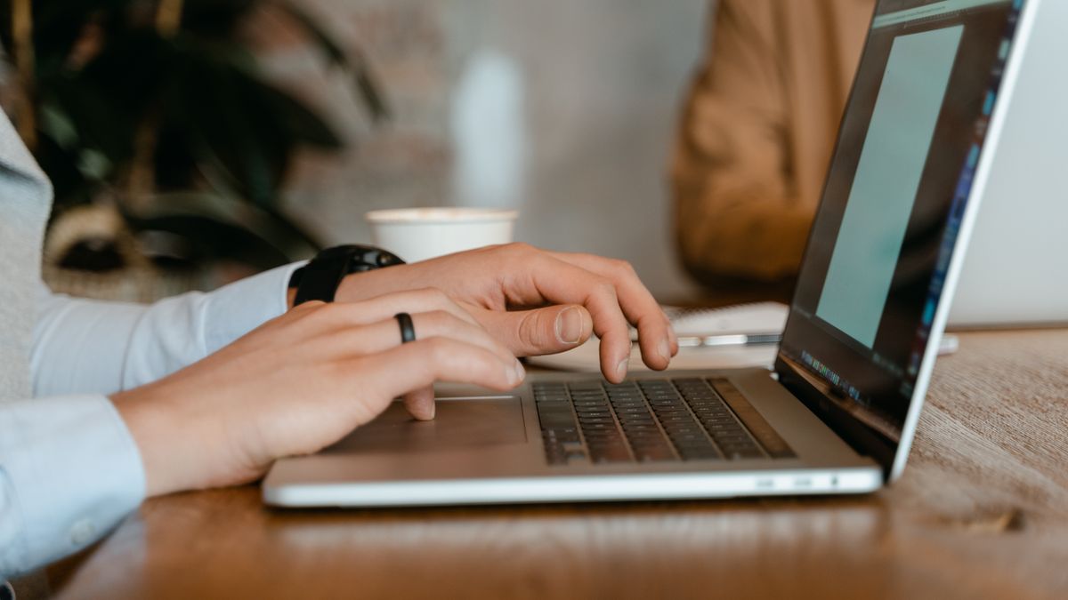 カフェのような空間でノートPCを操作している手元のイメージ