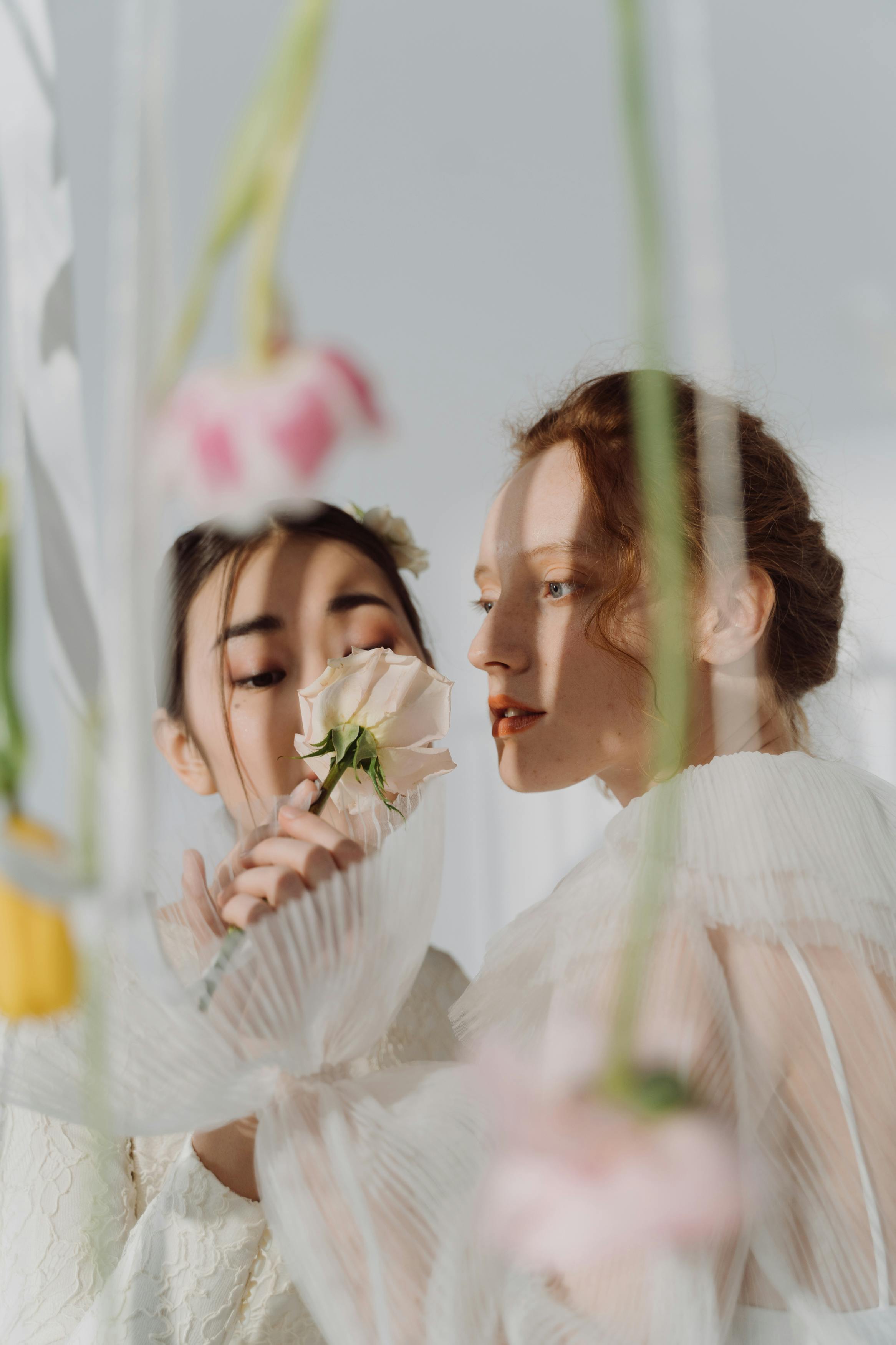 women in white dresses posing with a white flower