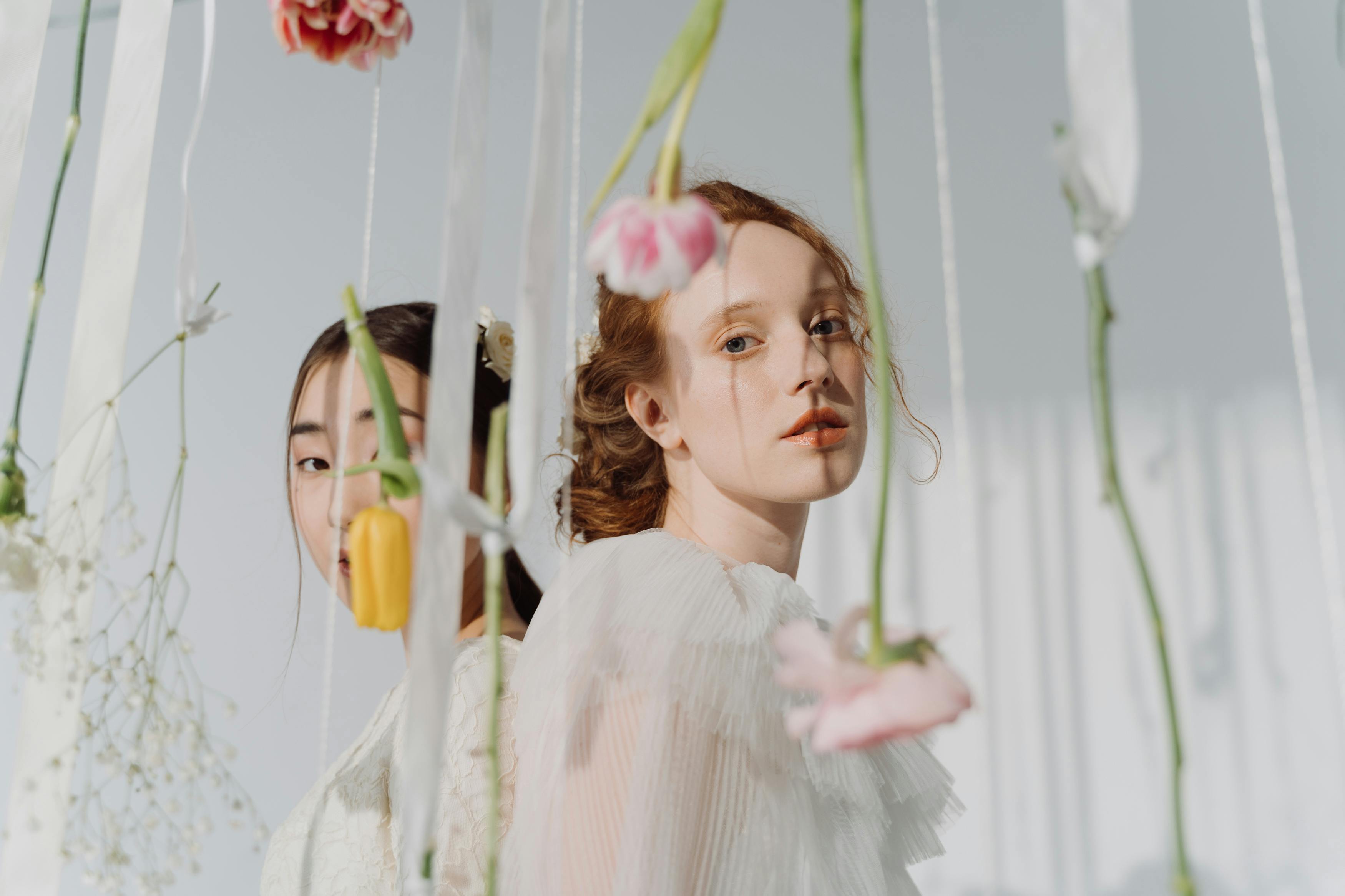 women in white dresses posing with flowers hanging upside down
