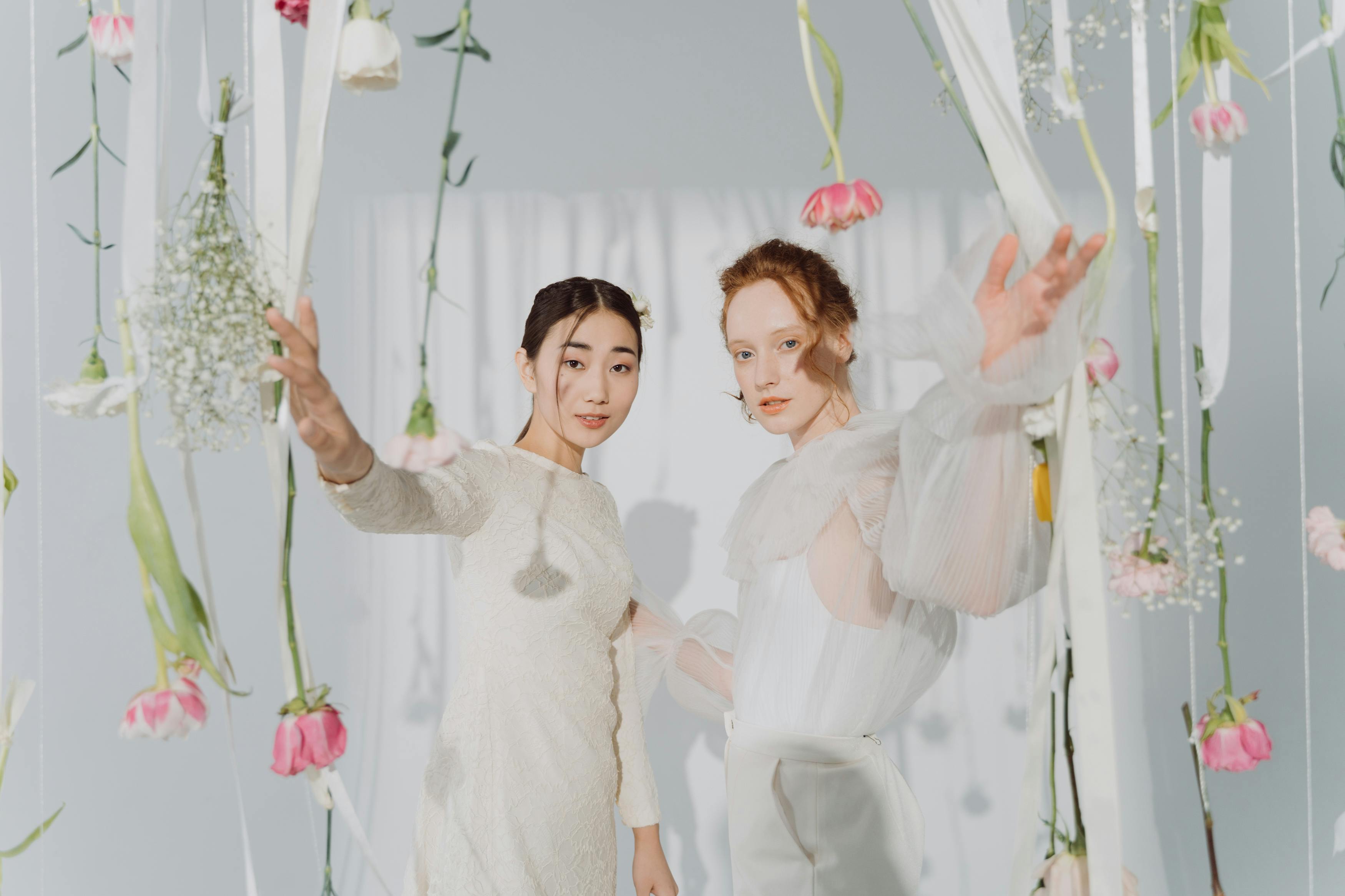 women wearing white dress while touching flowers