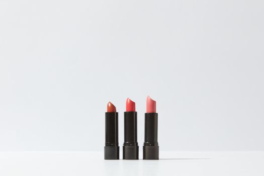 A minimalist display of three lipsticks on a white background, perfect for cosmetic themes.