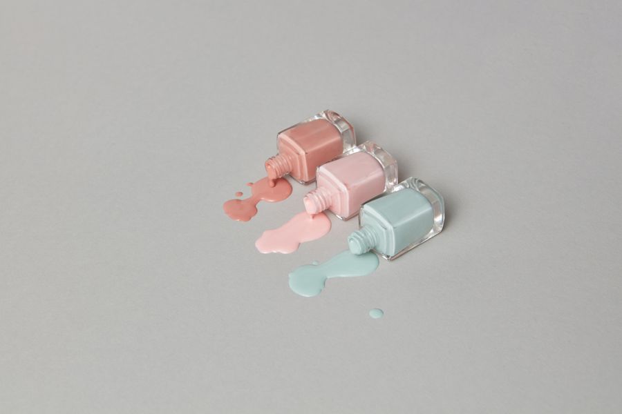 Two pastel bottles spilling colour on a grey background