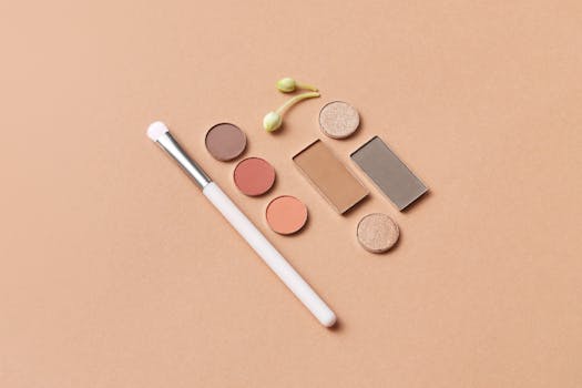 Stylish flat lay of eye shadows and makeup brush on a neutral background, perfect for beauty content.