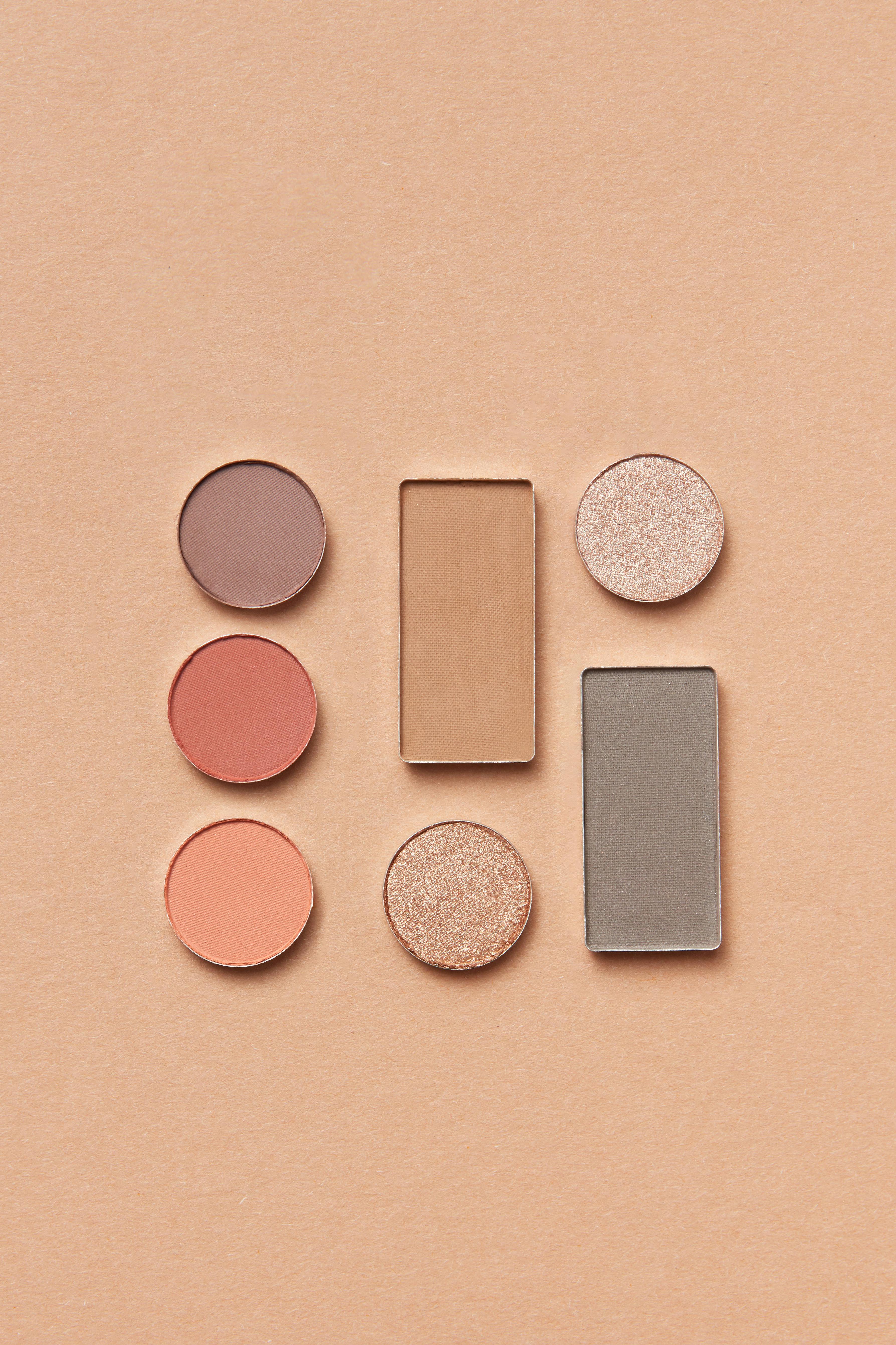 A top view of colorful makeup powders arranged on an orange surface, showcasing beauty and cosmetics.