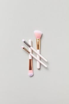 A set of three elegant makeup brushes arranged stylishly on a soft gray background for beauty concepts.