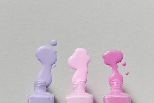 A minimalist image of colorful nail polish bottles with paint spilling on a gray surface.