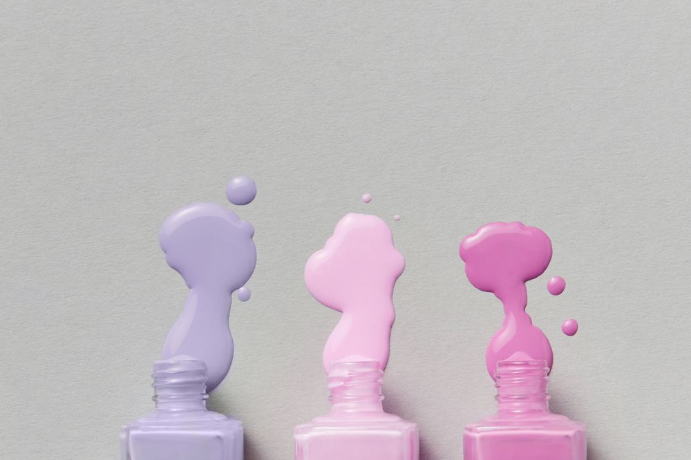 Lilac, pink and magenta lacquer poured from three bottles