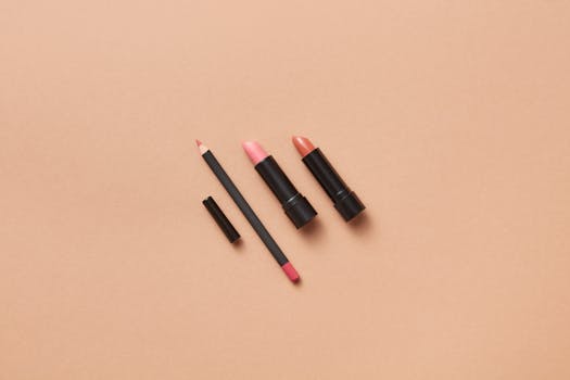 Simple and elegant flat lay of lipsticks and lip pencil on a beige surface, perfect for beauty and makeup promotions.