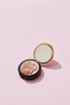 High angle view of a broken cosmetic powder on a pink background with copy space.