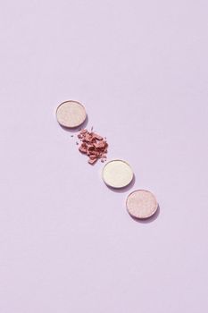 Close-up of three pastel eyeshadows in soft pink tones on a purple background, perfect for beauty themes.