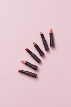 A selection of lipsticks in various shades artfully arranged on a soft pink background.