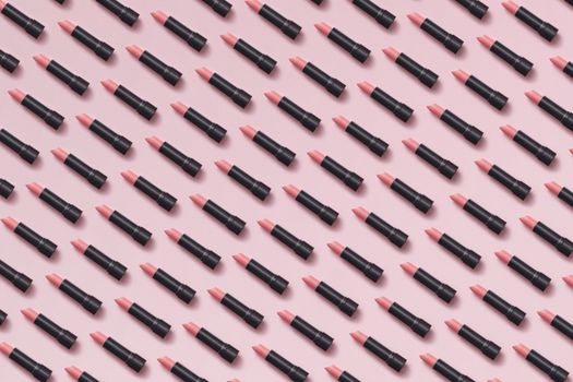 Flat lay of pink lipsticks arranged in a geometric pattern on pastel background.