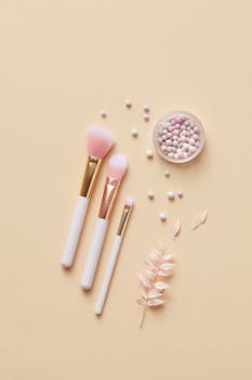 A flat lay of makeup brushes and pastel pearls on a beige background, perfect for beauty and cosmetics themes.