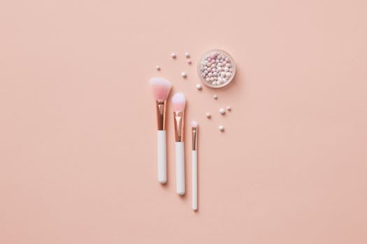 Flat lay of makeup brushes and pearlescent powder balls on a beige background. Ideal for beauty and cosmetic themes.