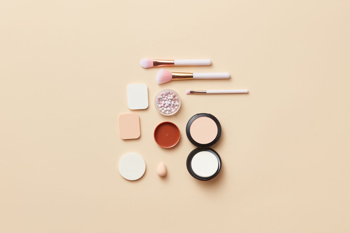 Makeup brushes and compacts on a beige background