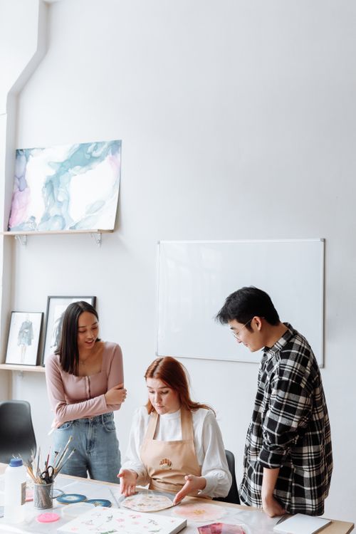 Free Three artists collaborate in a modern studio, surrounded by paintings and art supplies. Stock Photo