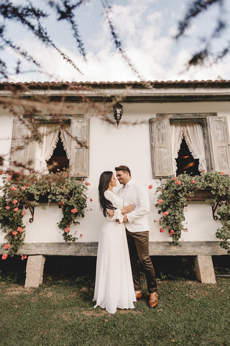 Happy Newlywed Couple Embracing Near Rustic House