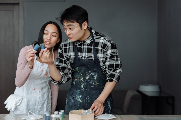 A Couple Holding Bottles Of Paints