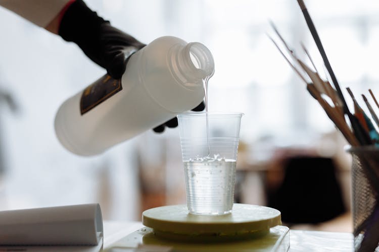 Person Pouring Resin In Plastic Cup