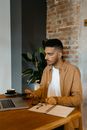Man in Brown Button Up Shirt Sitting beside Brown Wooden Table