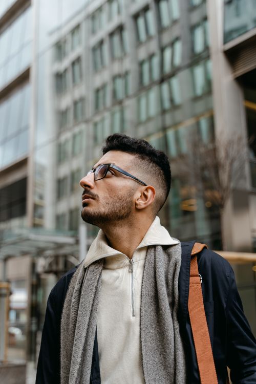 Free Profile of a man with glasses, looking up in a modern city environment. Stock Photo