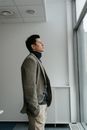 Man in Gray Sweater Standing Beside White Wall