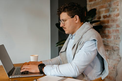 Free A Man in a Button Down Shirt Typing on a Laptop  Stock Photo