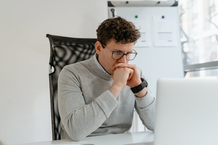 A Man In Gray Sweater Staring At His Laptop