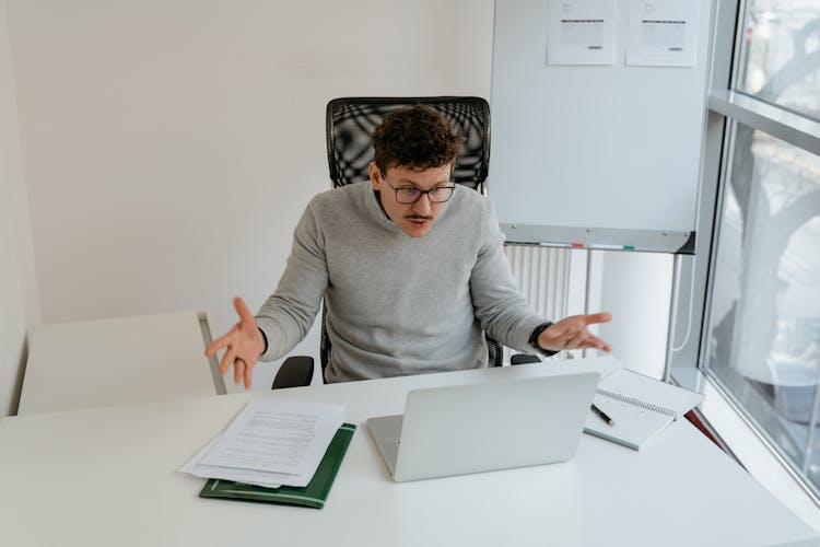 Man In Gray Sweater Wearing Eyeglasses While Working In The Office