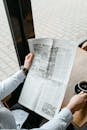 A Person Holding a Cup of Coffee and a Newspaper