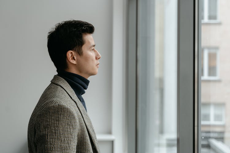 Man In Gray Checkered Suit Looking Outside The Window