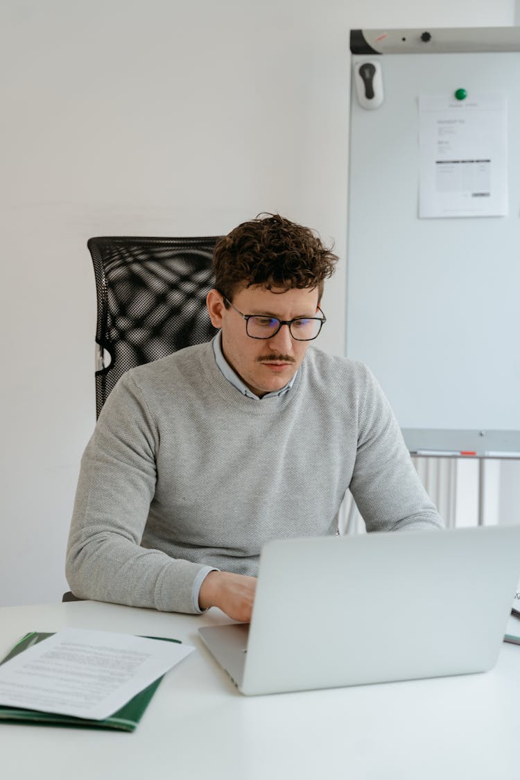 Man In Gray Sweater Wearing Eyeglasses While Working In The Office
