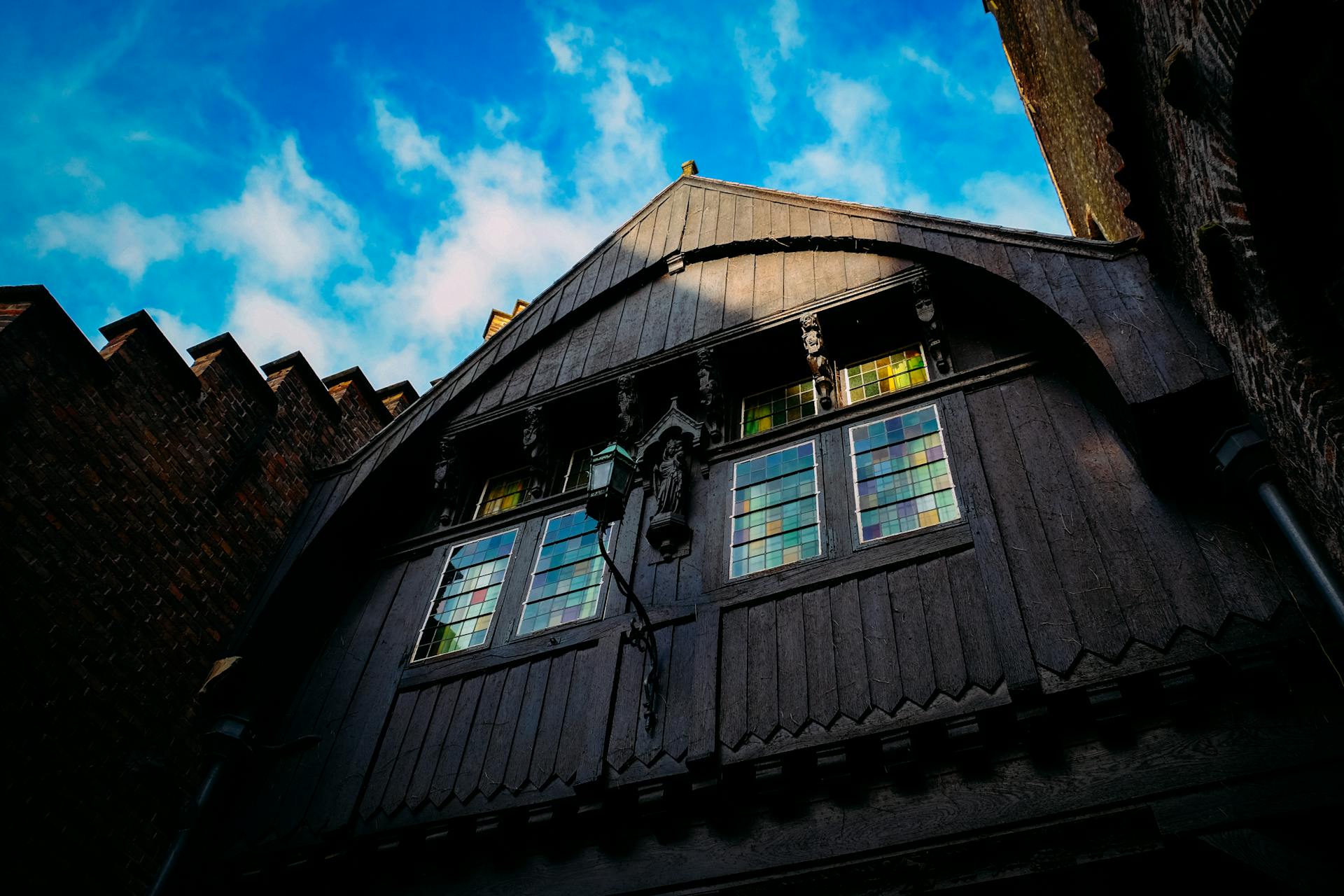 Low angle view of a historic building with intricate Gothic design and stained glass windows under a bright sky.