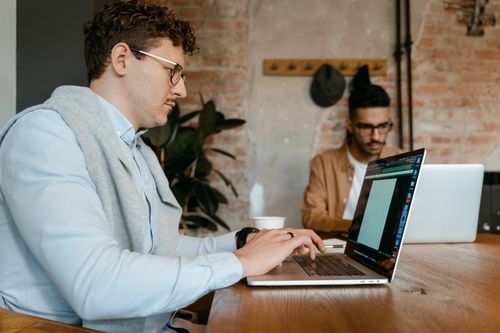 Free Two young men working on laptops in a stylish modern office setting. Stock Photo
