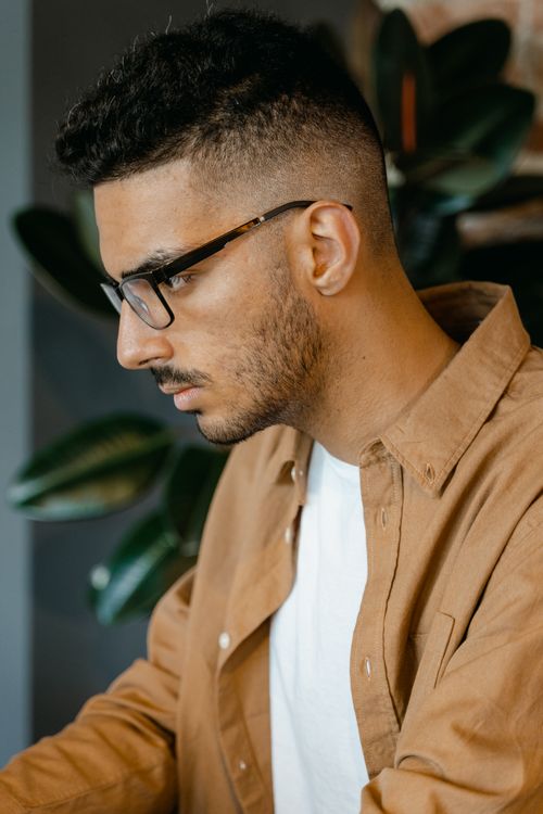 Free Side profile of an adult man with eyeglasses, wearing a brown shirt indoors. Stock Photo